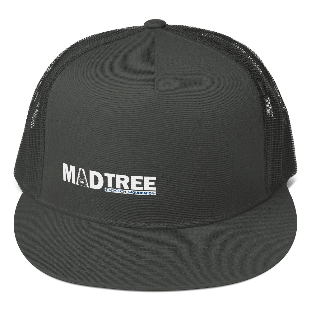 The Trucker Cap is a black mesh hat with a flat brim and features the white MADTREE FOUNDATION logo on the front panel.
