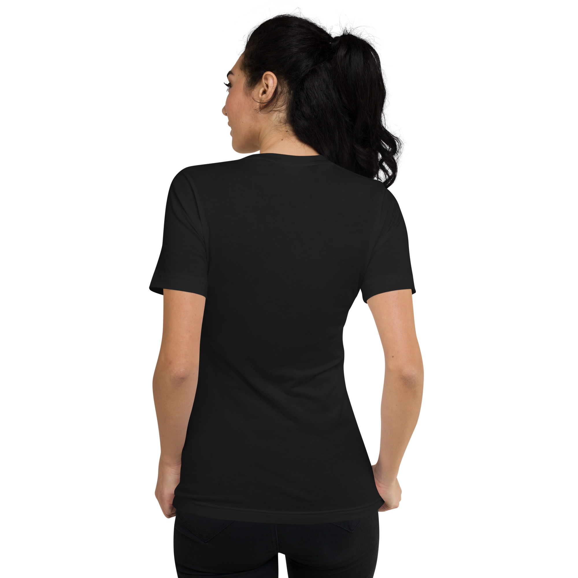 A woman with dark hair in a ponytail stands with her back to the camera, wearing the Mad Tree Unisex Short Sleeve V-Neck T-Shirt and black pants against a plain white background.