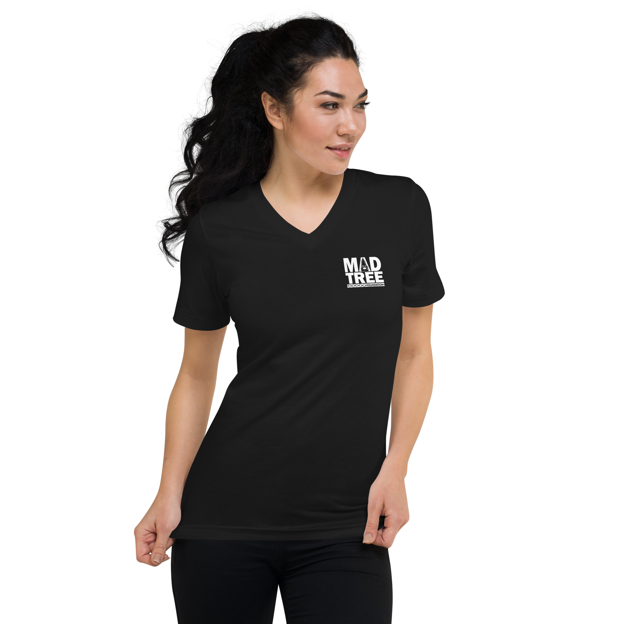 A woman with long dark hair models the Unisex Short Sleeve V-Neck T-Shirt - Mad Tree, featuring white "MAD TREE" text on the left chest, while standing against a plain white background and looking to her left.